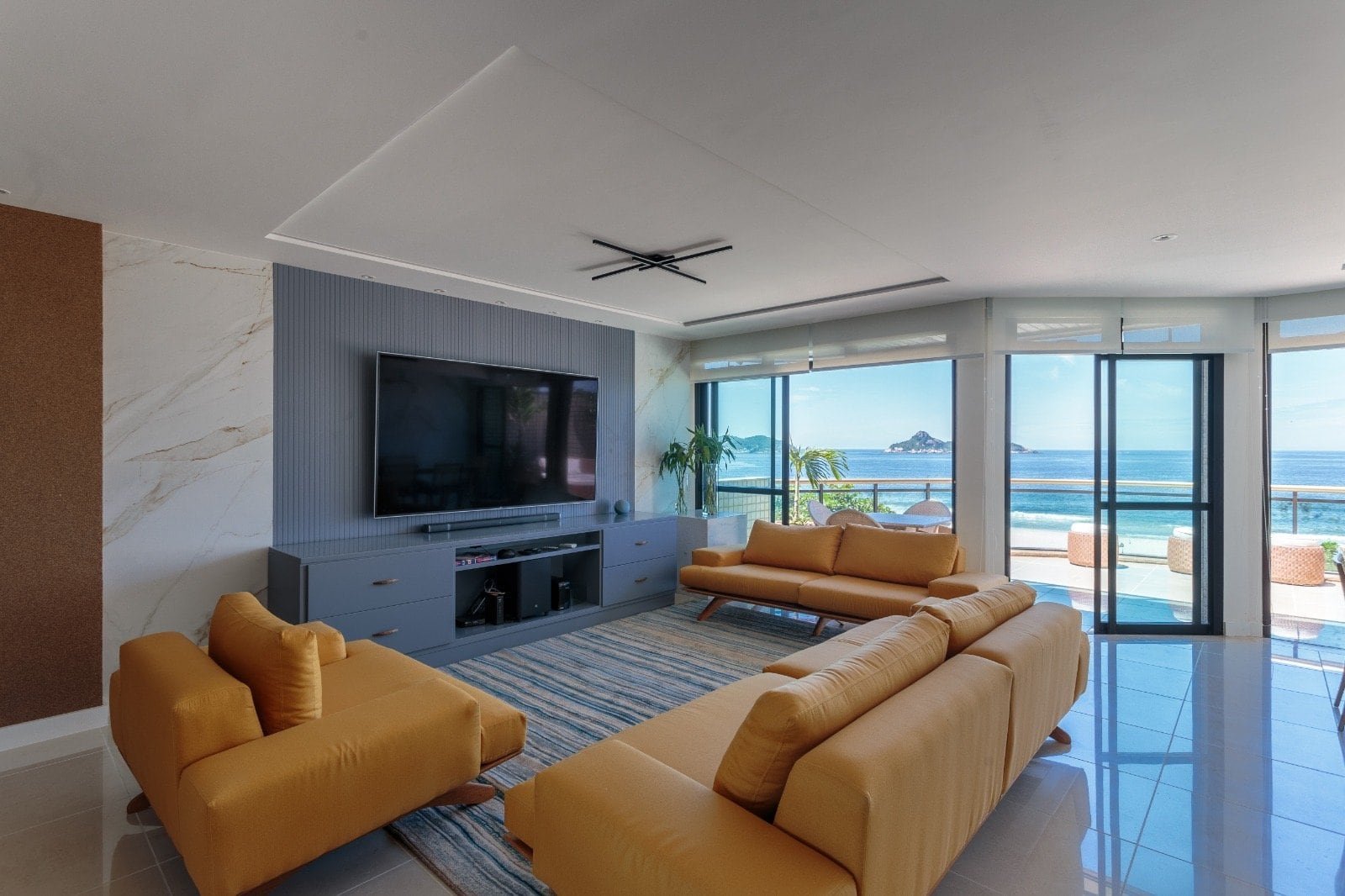 Conjunto de sofá de sala de estar moderna com vista para o mar, decoração elegante, TV de tela plana, janelas de vidro com vista para o oceano, ambiente aconchegante e sofisticado.