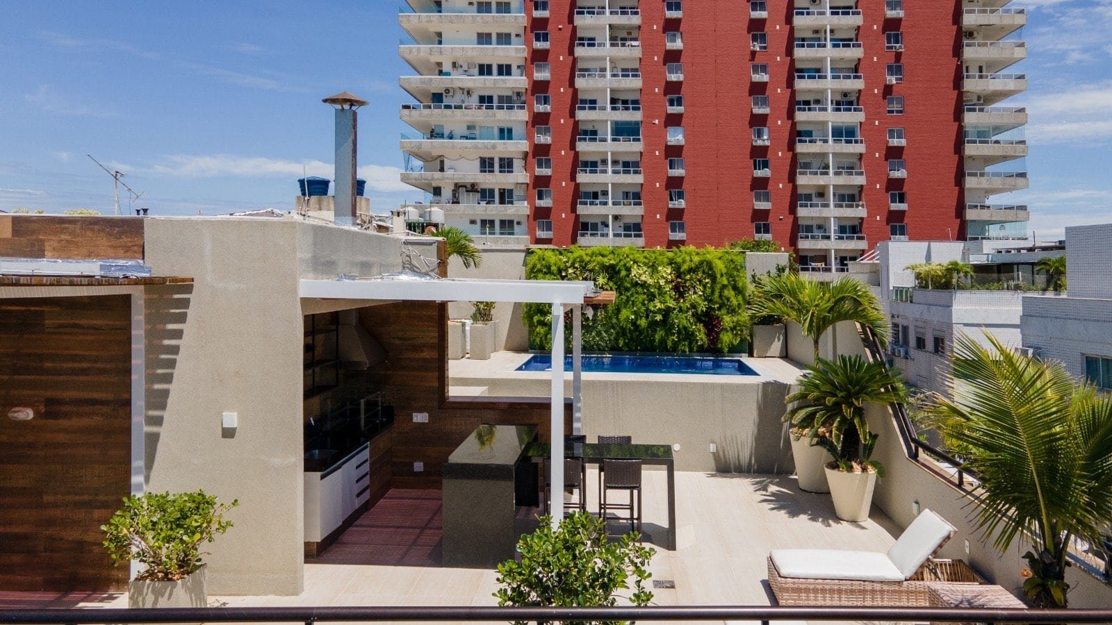 Varanda com piscina e lounge na cobertura de edifício residencial moderno em anexo a prédio alto em zona urbana de cidade grande em São Paulo.