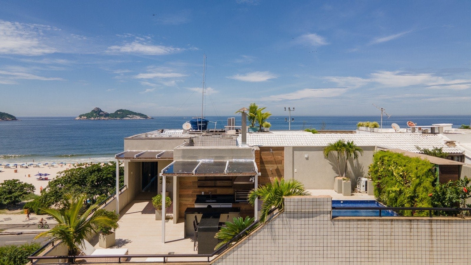 Vista panorâmica do mar e praia em uma residência de alto padrão com espaço para lazer, piscina e decoração moderna, com o oceano ao fundo e ilhas ao longe.
