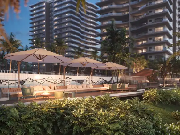 Luxuoso espaço de lazer ao ar livre no topo de edifício residencial com vista para torres modernas, áreas verdes, espreguiçadeiras, guarda-sóis, e decoração contemporânea, ideal para relaxamento e convivência.
