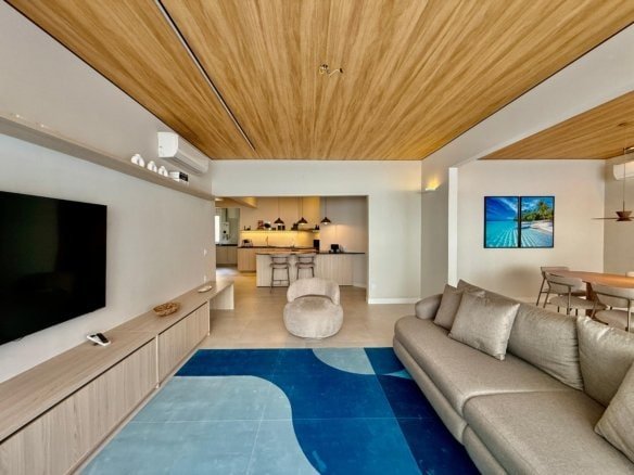 Moderno interior de sala de estar com decoração minimalista, sofá cinza, mesa de centro e painel de TV em tom natural, além de detalhes em madeira na estrutura e teto, ambiente sofisticado e aconchegante, perfeito para momentos de lazer e convivência.