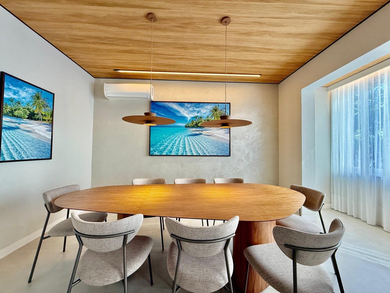 Linda sala de reuniões com decoração moderna e elegante, destaque para mesa de madeira oval e cadeiras confortáveis, ambiente com iluminação natural e detalhes que remetem ao litoral brasileiro.