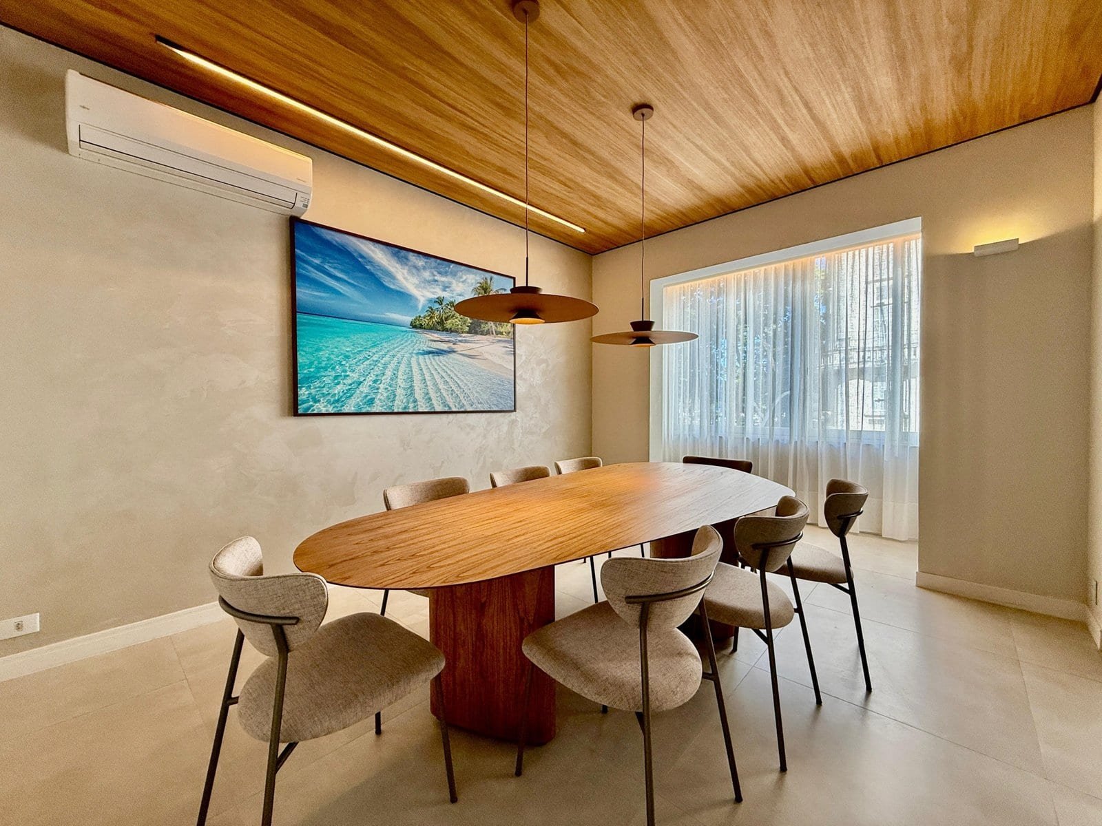 Luxuoso espaço de sala de reunião com mesa de madeira oval, cadeiras confortáveis, iluminação moderna, parede com tela de alta definição, cortinas de tecido leve e ar-condicionado, ideal para encontros de negócios sofisticados.
