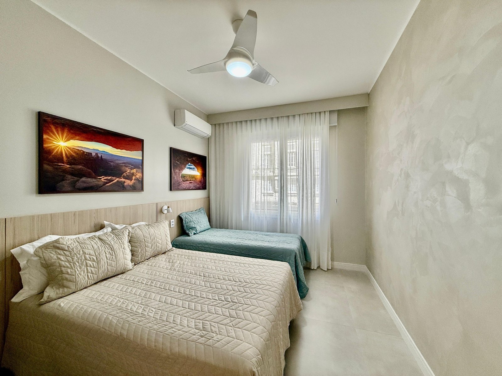 Visão de quarto de hotel com cama de casal e cama de solteiro, decoração moderna, iluminação natural, paredes claras e arte contemporânea, ideal para hospedagem confortável em Mônaco.