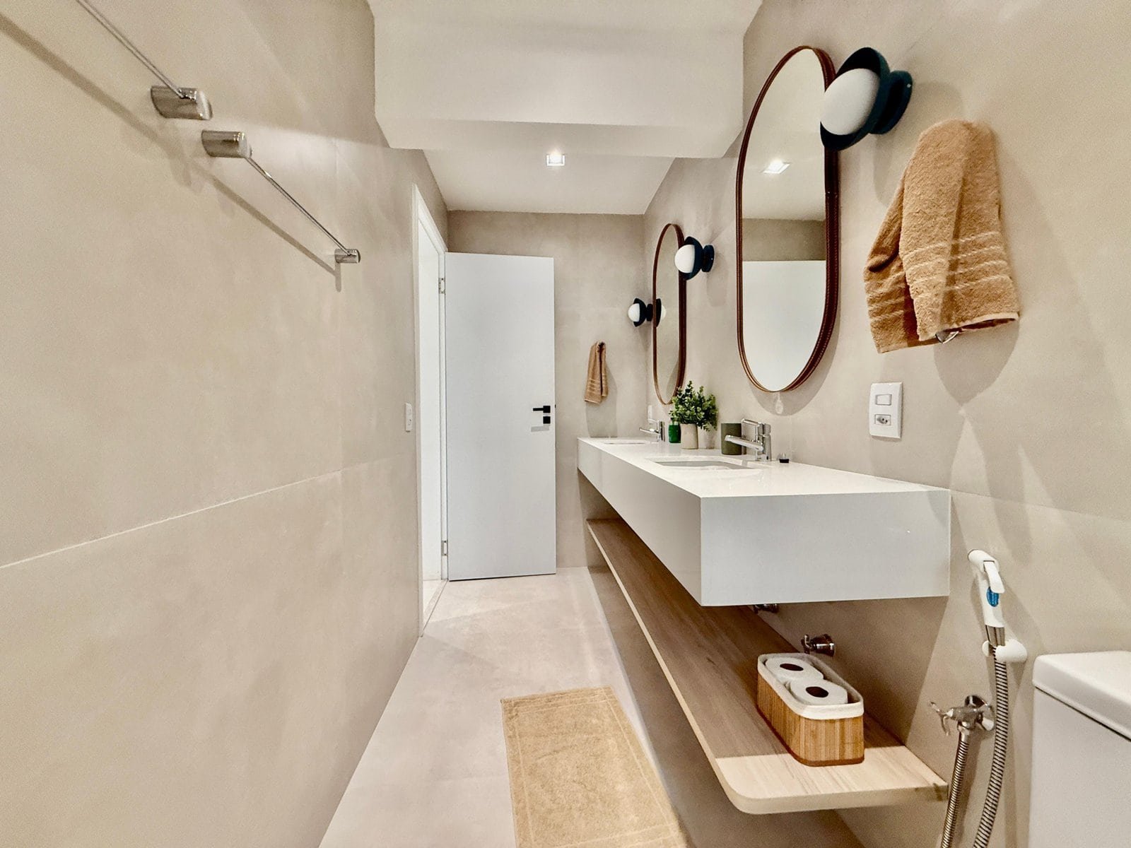 Moderno banheiro com pia de design minimalista, espelhos ovais, iluminação embutida, detalhes em madeira e decoração clean, ideal para conforto e estilo em projetos de arquitetura e design de interiores.