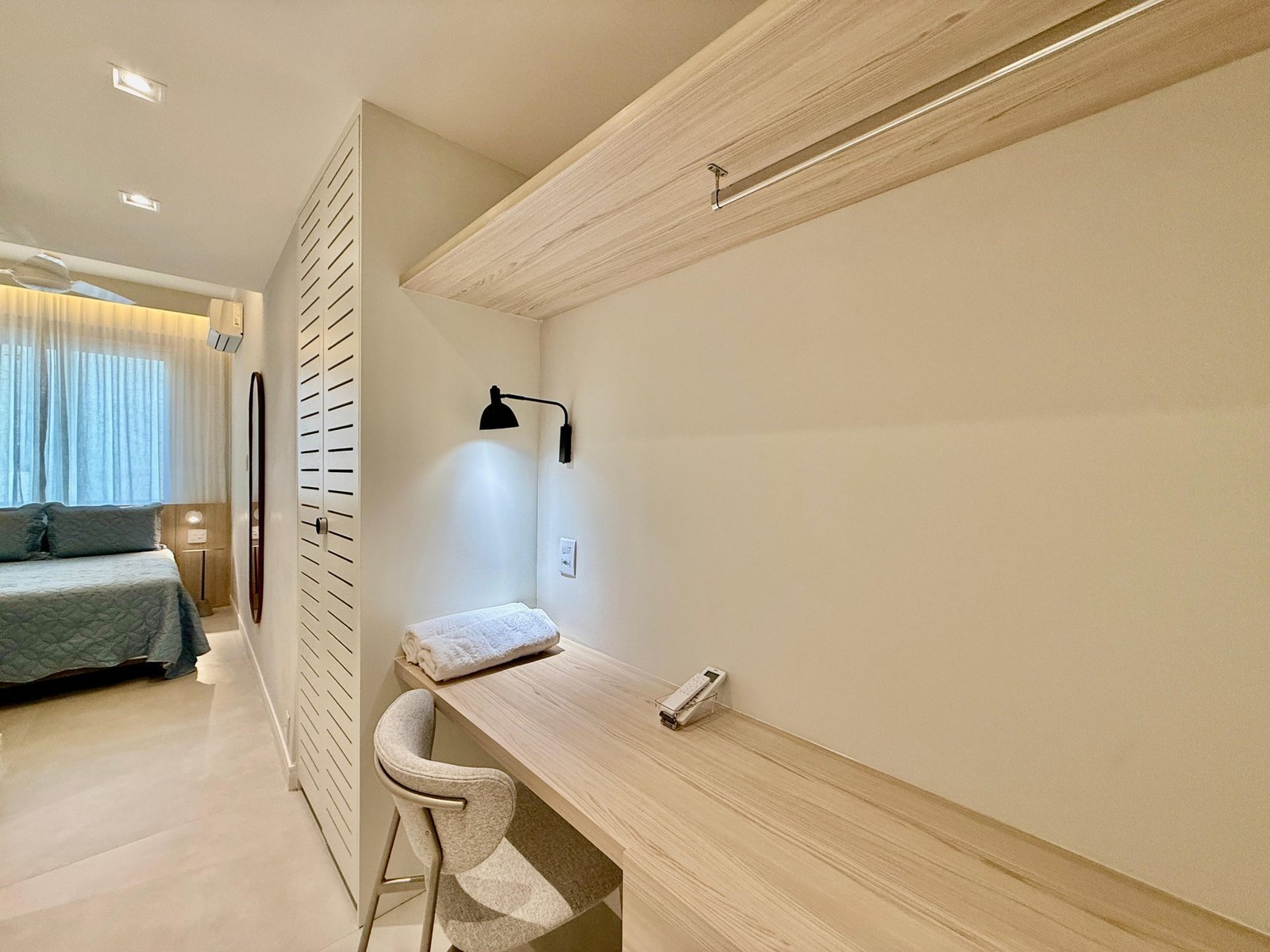 Escrivaninha moderna em quarto de hotel com iluminação dedicada, espaço de trabalho funcional, presente na suíte do Gruppo Monaco, destacando design de interiores elegante e confortável.