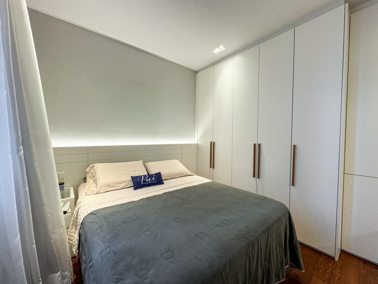 Quarto de hotel moderno com cama de casal, armário embutido branco e detalhes de iluminação suave, ideal para hospedagem confortável e elegante.