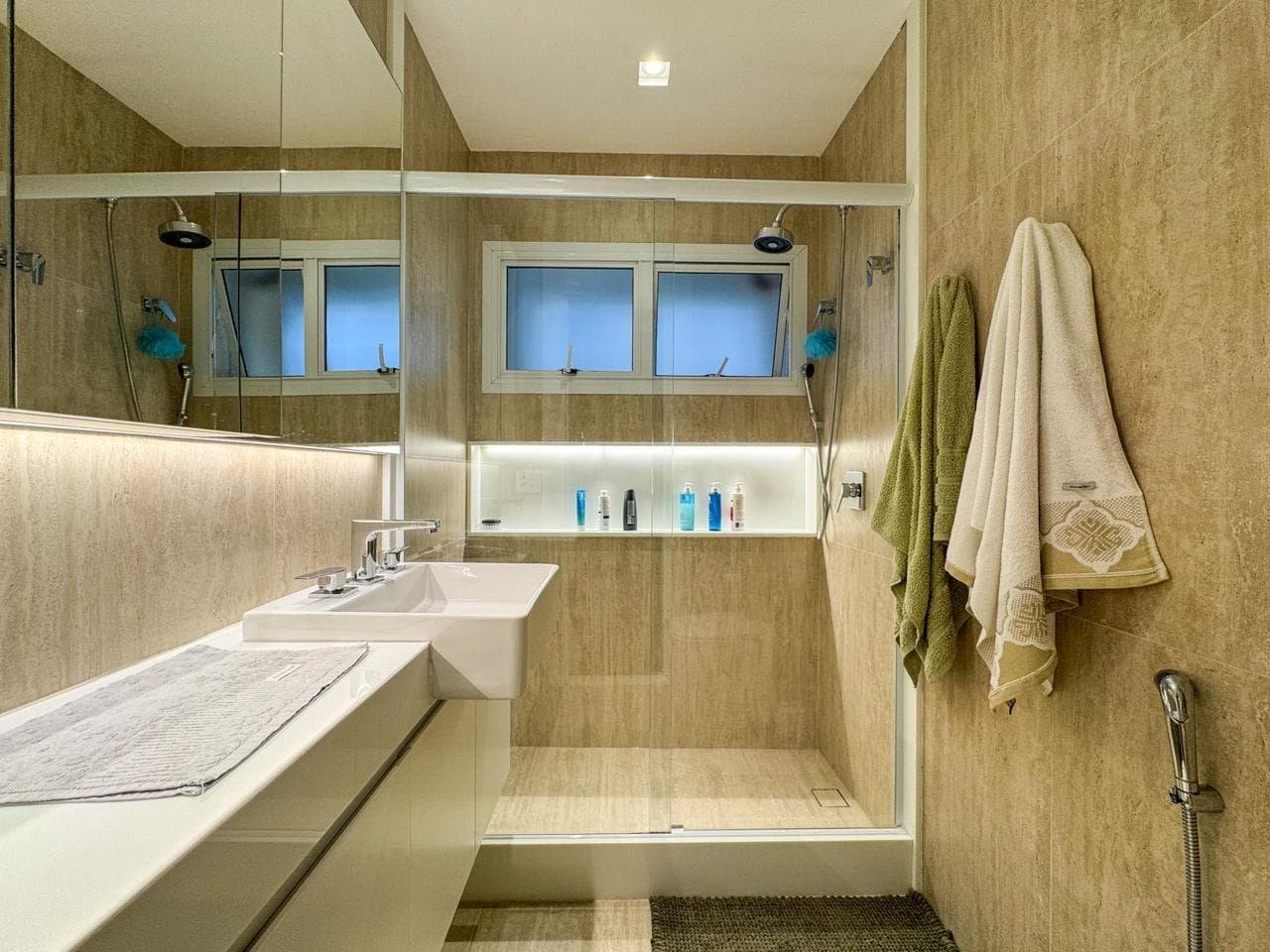 Luxo banheiro contemporâneo com bancada em mármore, solário de vidro, banho a vapor, banheira, decoração moderna, hotel cinco estrelas, detalhes elegantes, revestimentos em pedra bege, iluminação sutil, toalhas macias e espelhos amplos.