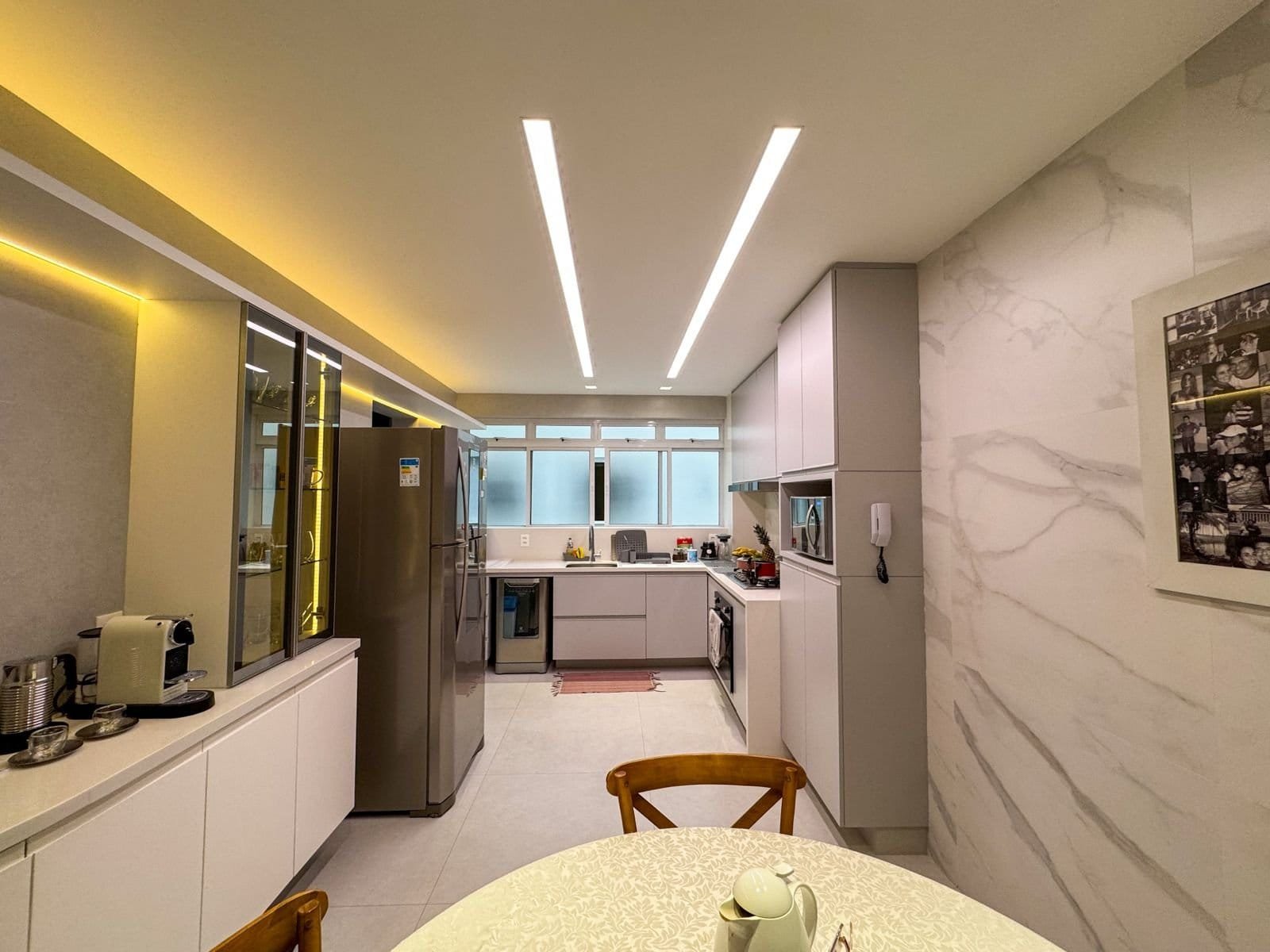 Reforma de cozinha moderna com iluminação embutida e acabamento elegante em granito branco. Ambiente funcional e sofisticado, ideal para cozinhar com conforto e estilo.