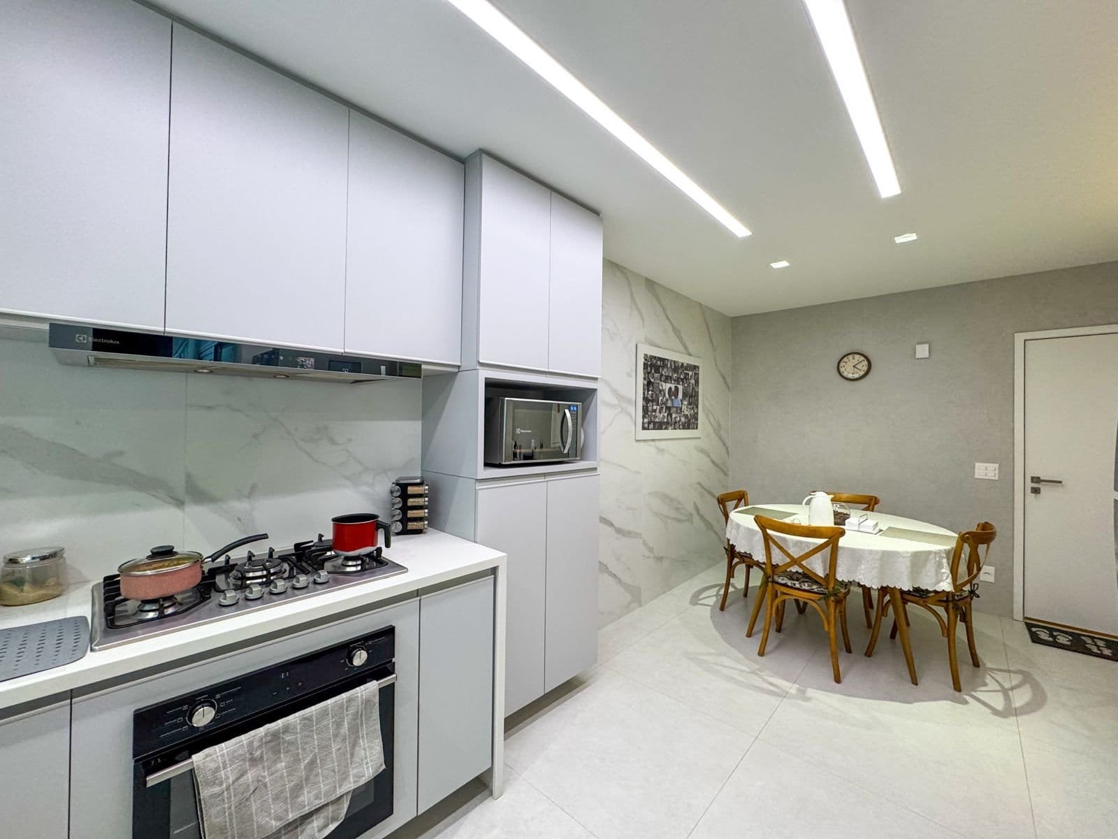 Moderno espaço de cozinha com acabamento de alta qualidade, balcões brancos, eletrodomésticos embutidos e iluminação eficiente, ideal para residências sofisticadas.