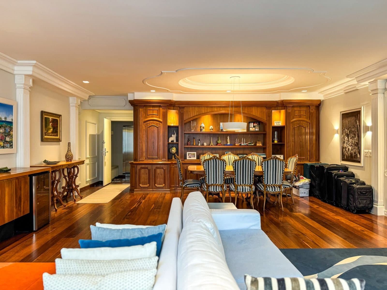Luxuoso ambiente de sala de jantar com móveis em madeira escura, paredes decoradas com quadros e iluminação suave, ideal para eventos e reuniões elegantes no conforto de casa.