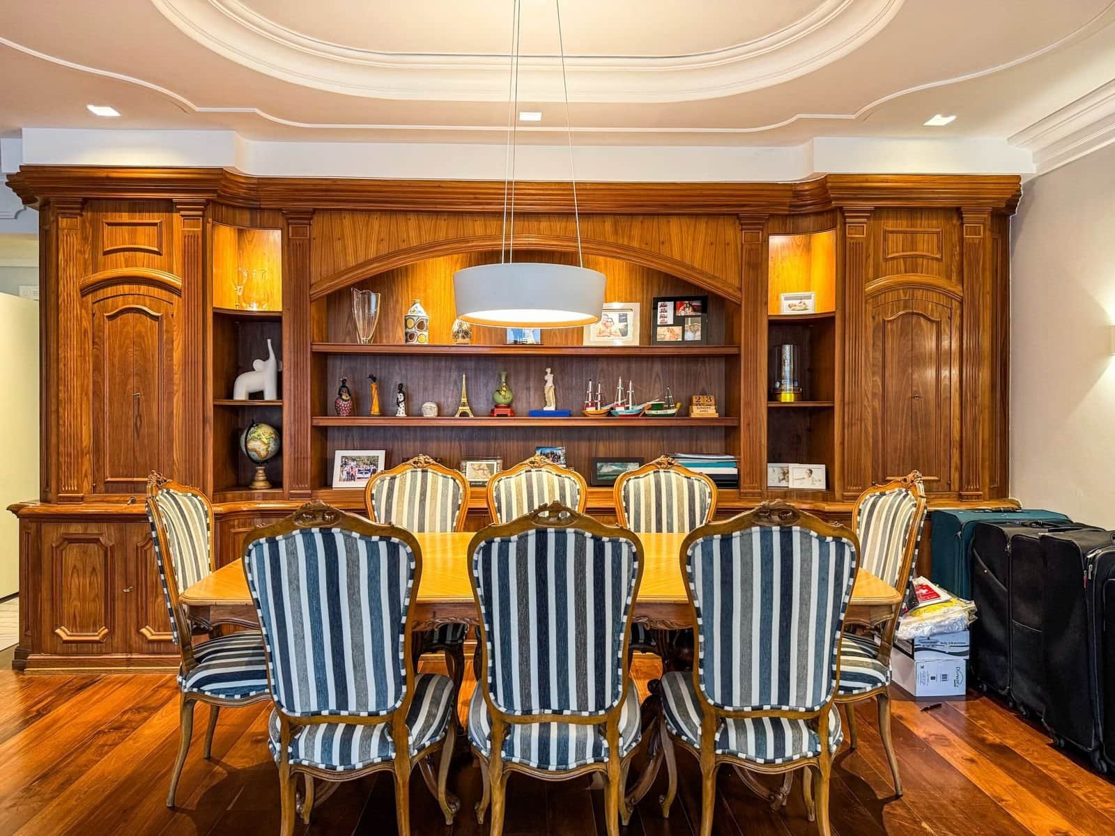 Conjunto de sala de jantar com móveis de madeira de alta qualidade, incluindo uma mesa ampla e cadeiras com revestimento de listras azuis e brancas, ideal para ambientes residenciais ou comerciais de alto padrão.