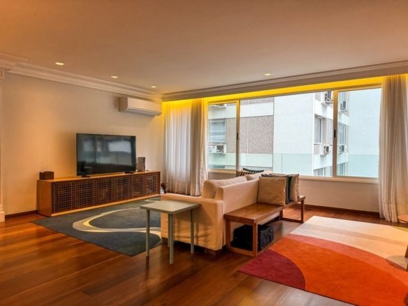 Sofá confortável de descanso na sala de estar com vista para janela grande, iluminação amena, decoração moderna, elegância residencial, ambiente acolhedor, design contemporâneo, móveis de madeira, espaços de convivência, conforto e sofisticação, apartamento de alto padrão, imóveis de luxo, arquitetura urbana, vista para edifícios, atmosfera aconchegante, iluminação indireta, interior sofisticado, grupo Monaco, imóveis residenciais.